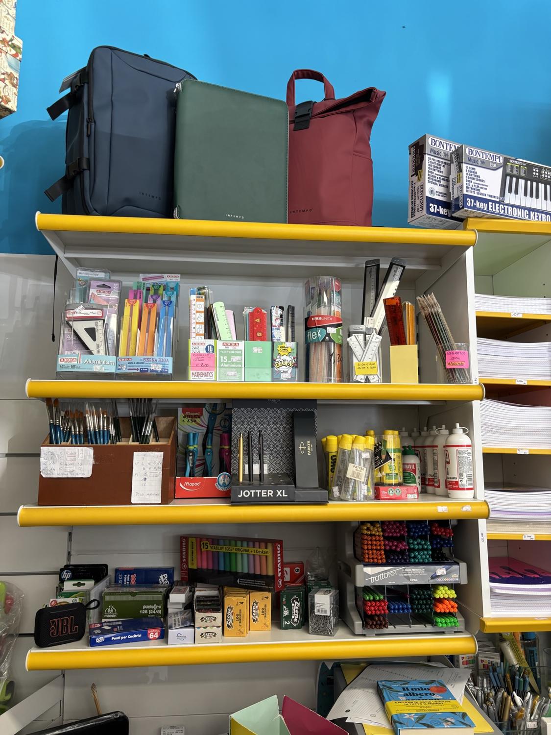 Scaffale della cartoleria con zaini, squadre, penne e colla